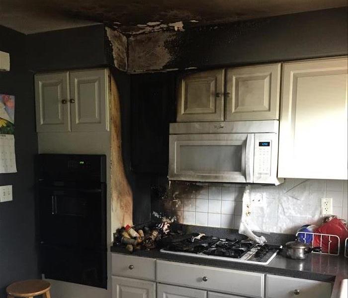 Kitchen cabinets, a microwave, and ceiling with fire and smoke damage