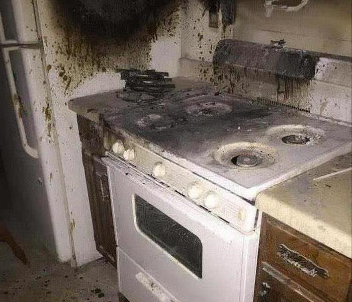 A stove and refrigerator covered in smoke damage from a fire