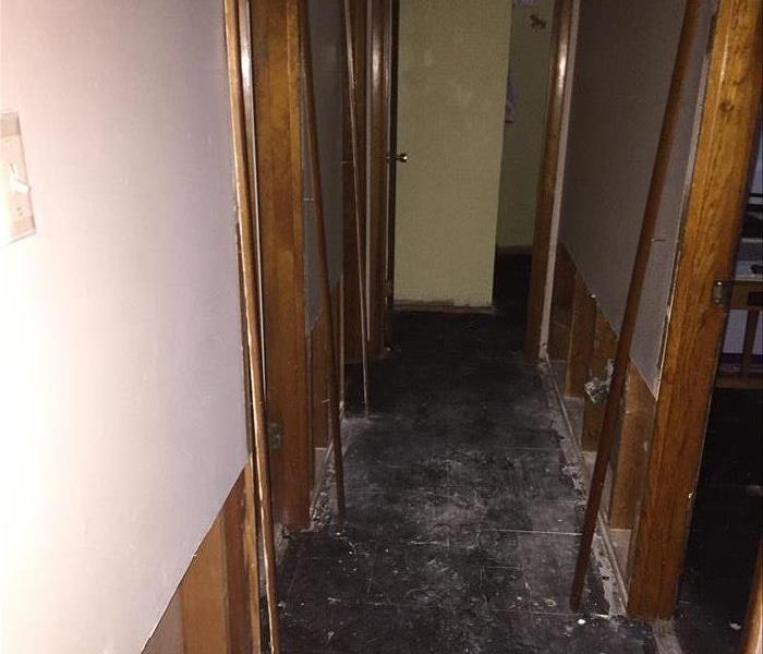 A hallway with drywall and  flooring ripped up from water damage. 