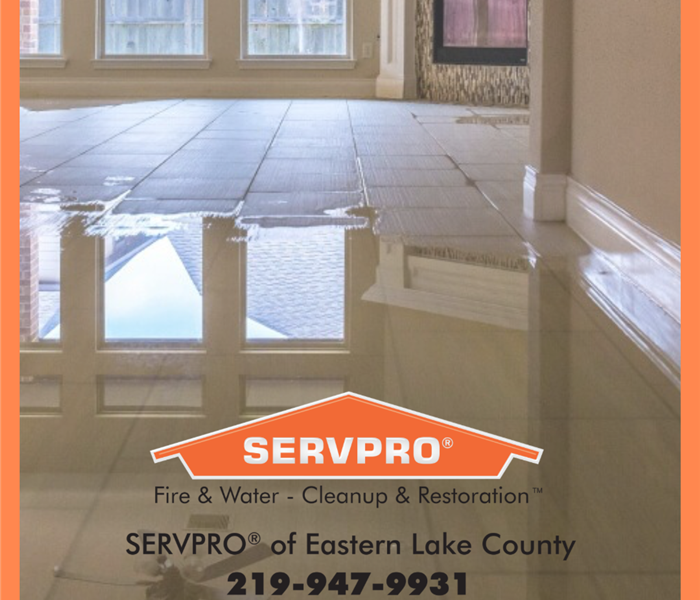 A flooded living room with servpro logo and phone number 